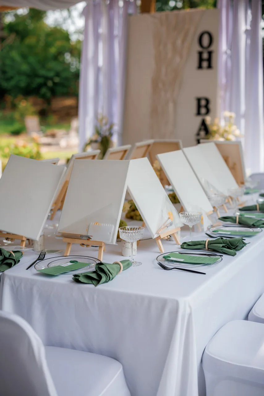 Kids painting party table with easels, canvases and crystal cups on white linens