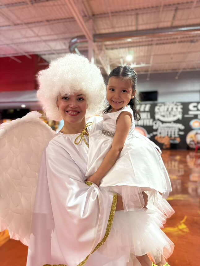 Angel entertainer holding a smiling child at a themed event