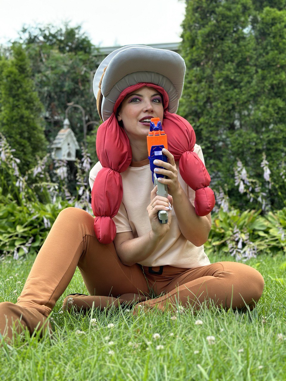 Entertainer in a colorful game-themed costume holding a toy blaster outdoors