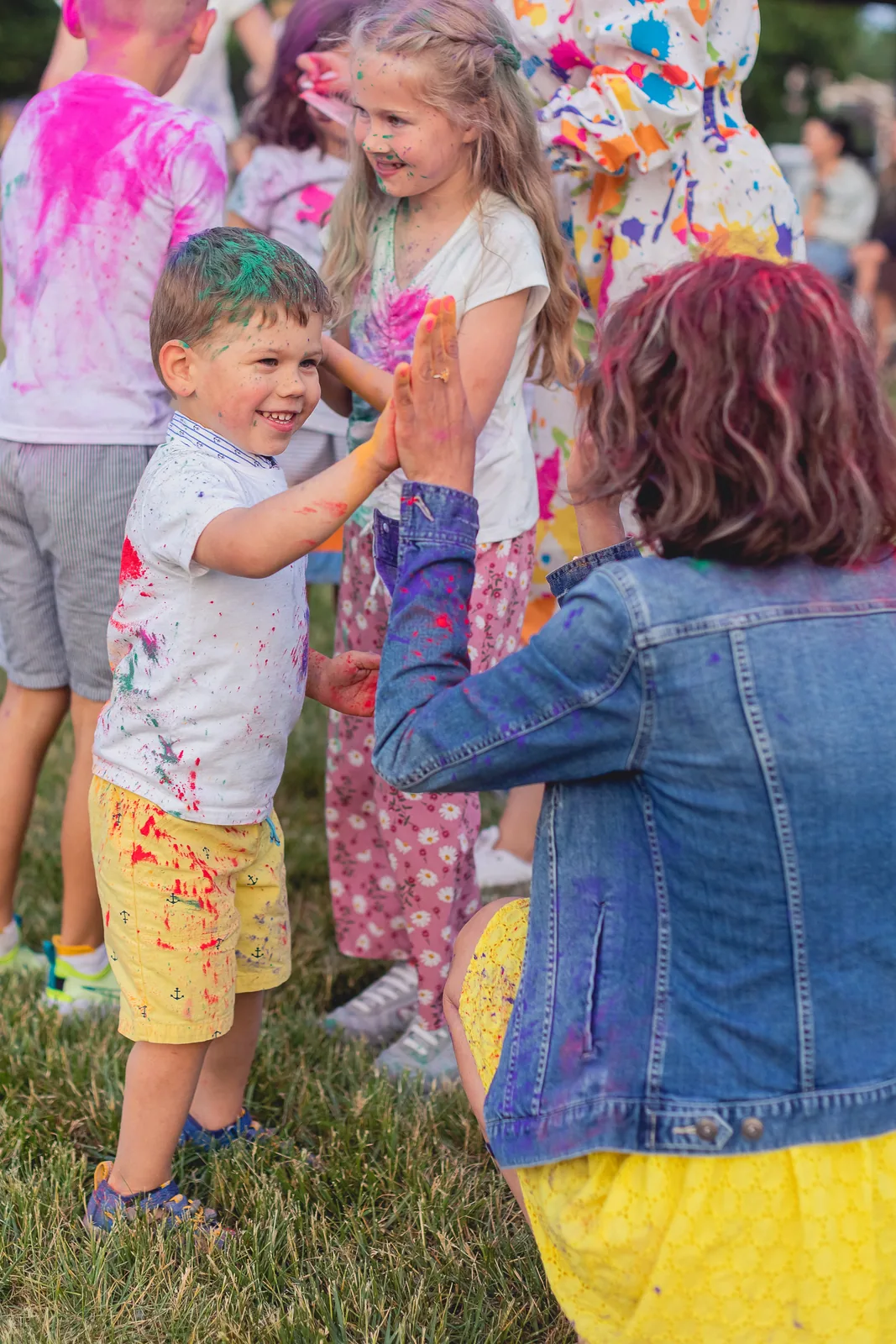 Children giving high fives during a colorful outdoor powder party