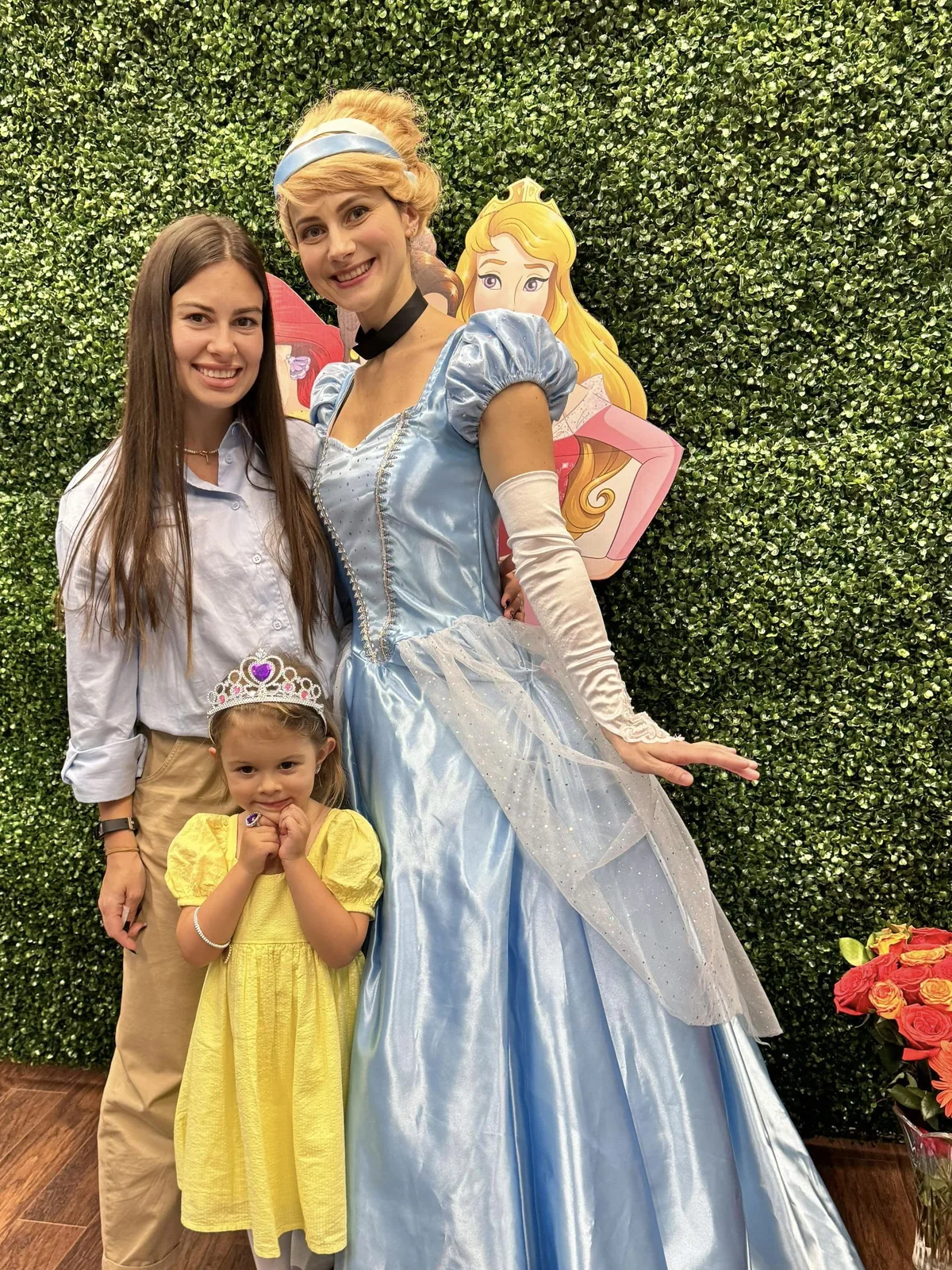 Cinderella character posing with a child and parent at a princess-themed party