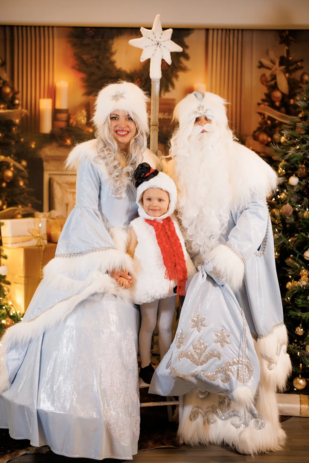 Snegurochka and Ded Moroz posing with child in snowman costume
