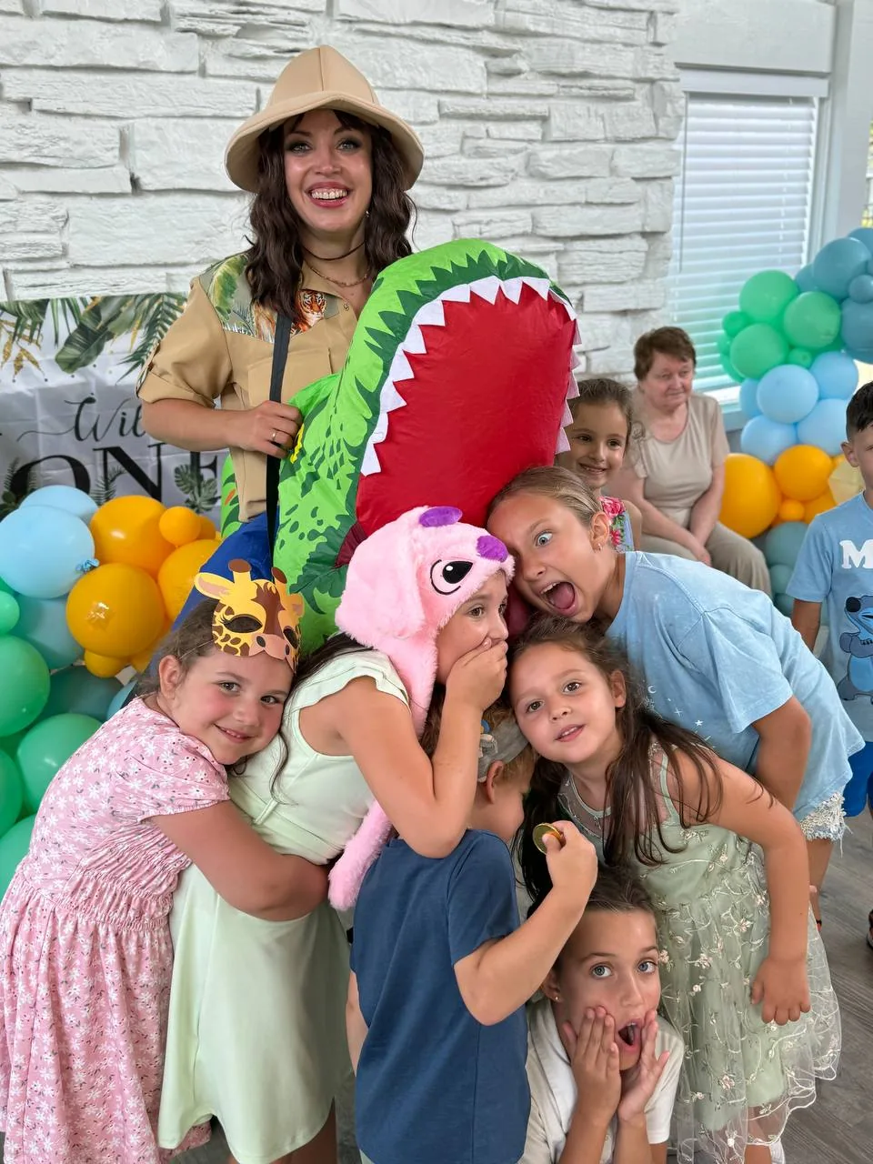 Kids posing with a safari-themed entertainer at a dinosaur party