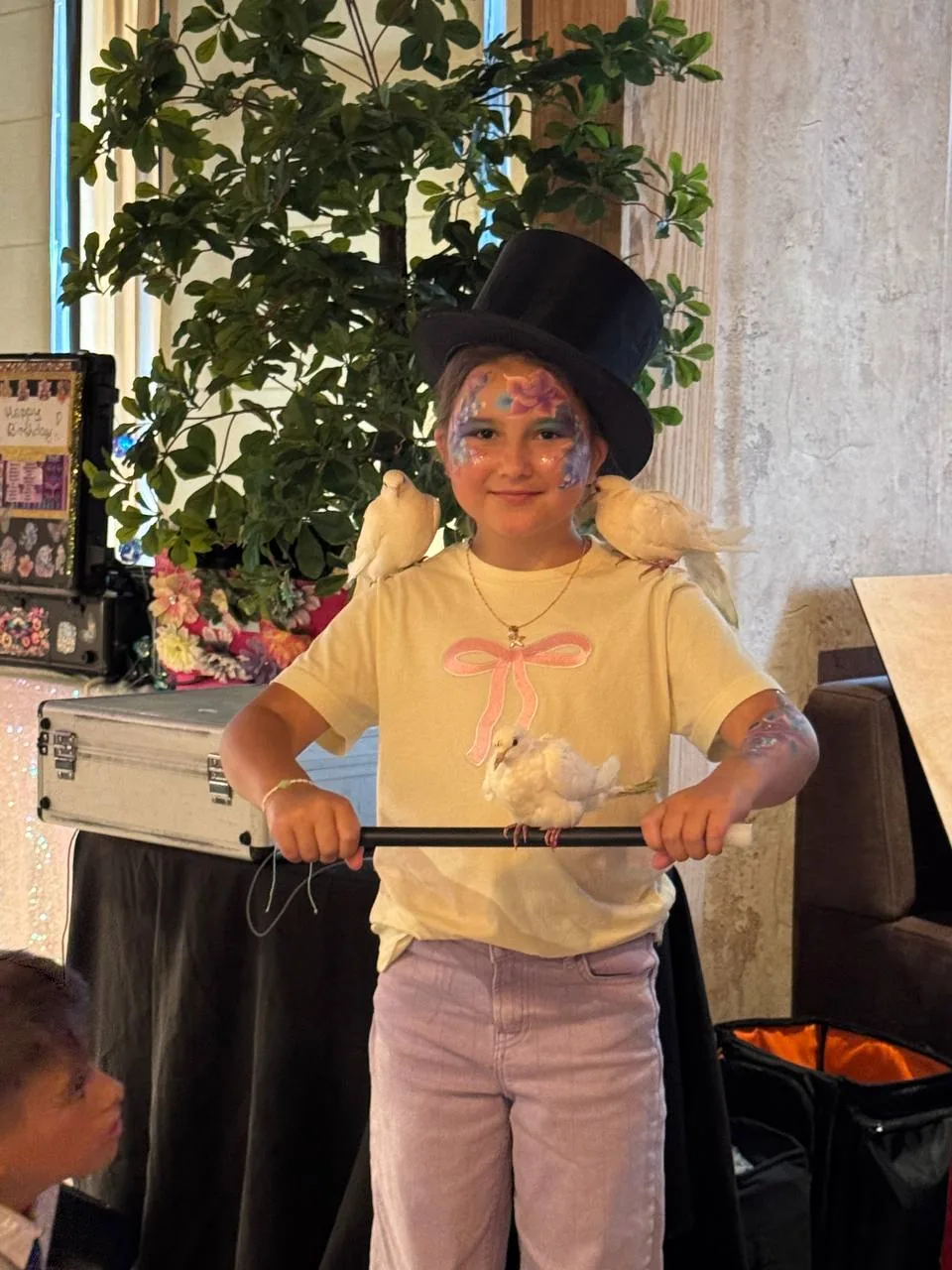 Child dressed as a magician holding doves during a magic show