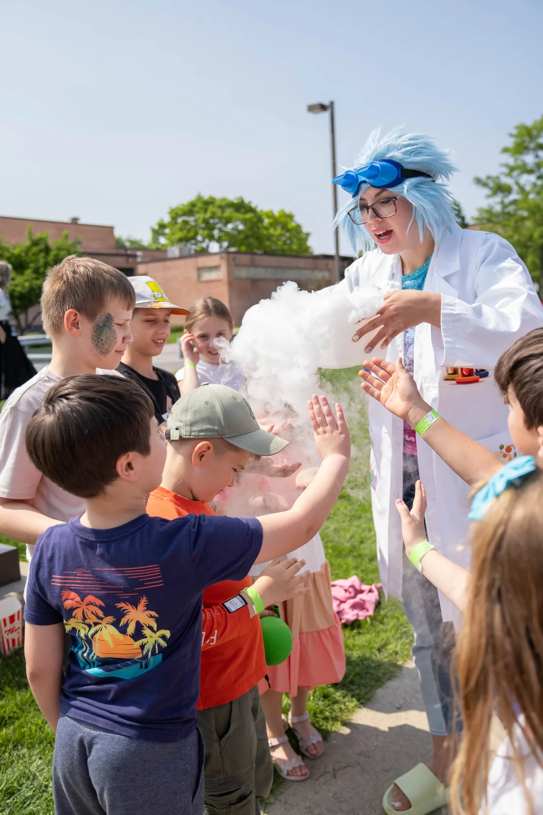 Kids gathered around a performer doing a science experiment with smoke